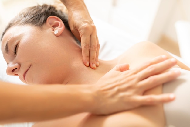 A patient completely relaxed enjoys receiving a massage from her physiotherapist in the neck area