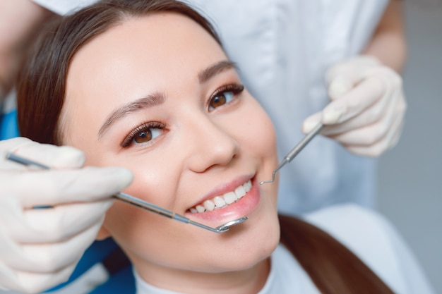 Patient in dental chair. Beautiful young woman having dental treatment at dentist's office.