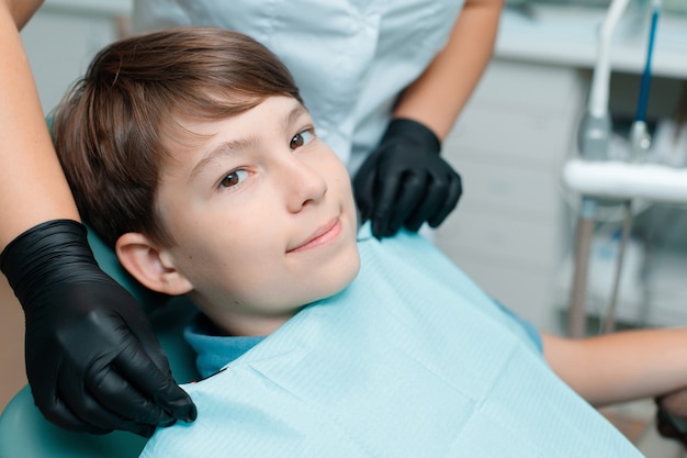 Пациент в стоматологическом кресле Мальчик-подросток, имеющий стоматологическое лечение в офисе стоматолога