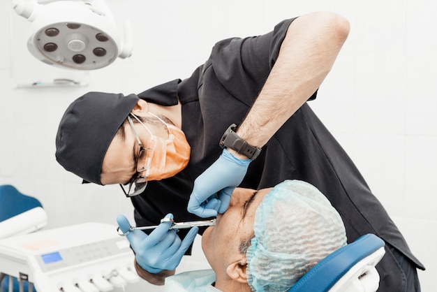 Patient and dentist during implant placement operation. Real operation. Tooth extraction, implants. Professional uniform and equipment of a dentist. Healthcare Equipping a doctor workplace. Dentistry