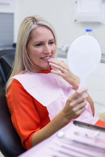 Patiënt die haar tanden in spiegel controleert