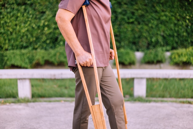 Patient elderly asian woman using crutches support broken legs for walking at public park,Physical therapy concept