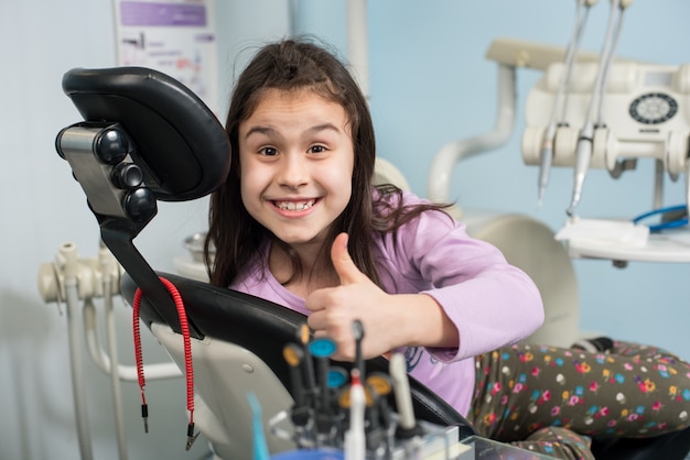 Patient girl showing thumbs up at dental clinic office