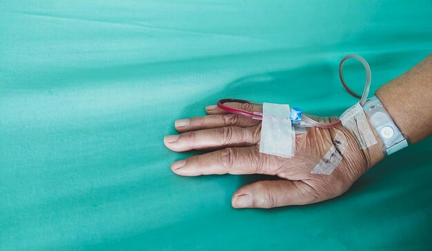 病院のベッドに生理食塩水ホースで患者の手