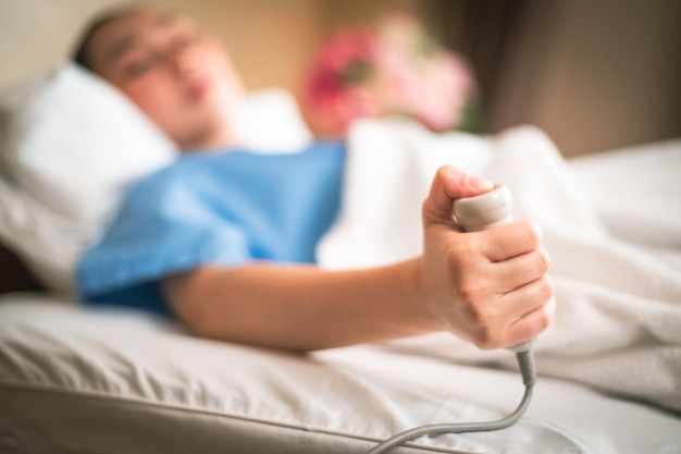 Patient in a hospital room calling a nurse A hand holding press emergency button in hospital room Emergency button for hospital patients