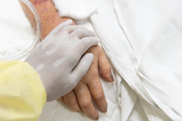 Patient in the hospital with saline intravenous and relatives patient hand holding a elderly patient hand