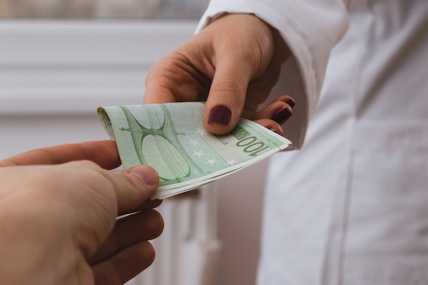 Patient is giving money to a doctor in hospital,