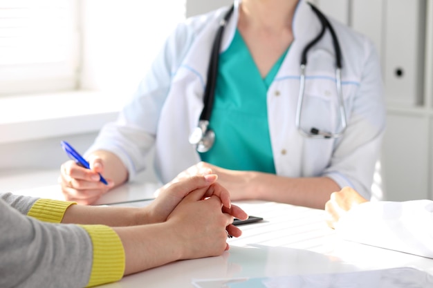 Patient listening to his doctor sitting at the table. Hands close-up.