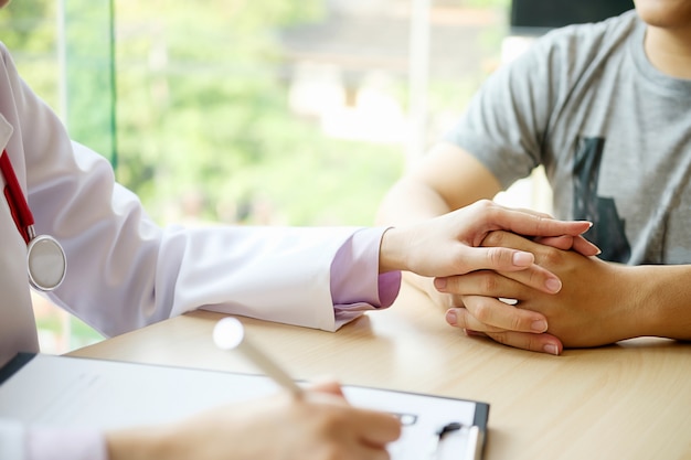 Patient listening intently to a male doctor explaining patient symptoms or asking a question as they discuss paperwork together in a consultation