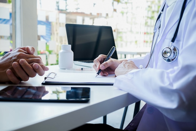 Patient listening intently to a male doctor explaining patient symptoms or asking a question as they discuss paperwork together in a consultation