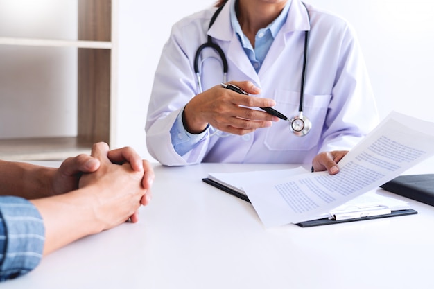 Patient listening intently to a male doctor explaining patient symptoms or asking a question as they discuss paperwork together in a consultation