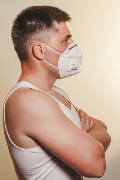 Patient man in medical mask on self isolation during quarantine and coronavirus pandemic stands with arms crossed new