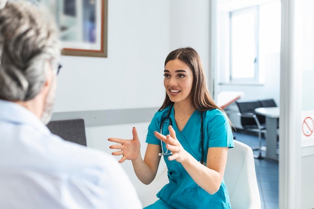 Patiënt met dokter in de wachtkamer van het ziekenhuis die zijn symptomen bespreekt Jonge vrouwelijke dokter die met haar patiënt praat en hem zijn opties en therapie uitlegt