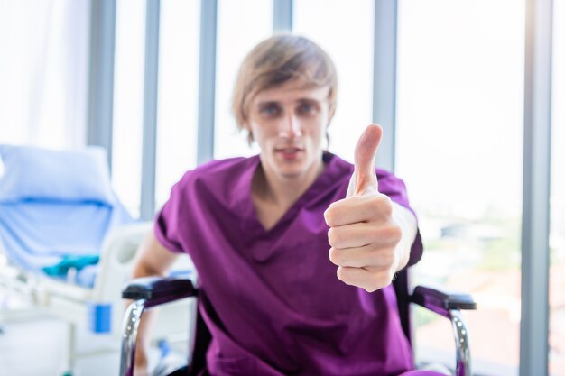 patient sit in a wheelchair showing thumbs up with smiley face