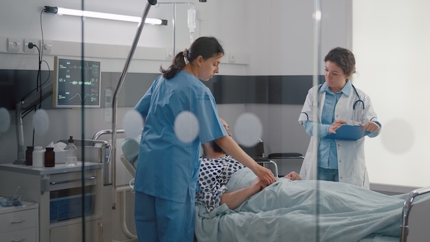patient sitting in bed having respiratory illness while medical nurse monitoring heart pulse