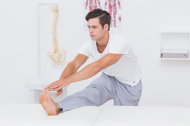 Patient stretching his leg on bed 