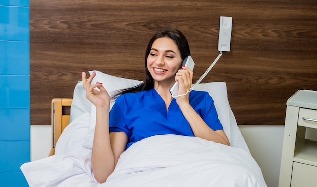 Patient talking on the phone in hospital bed. Young caucasian woman.