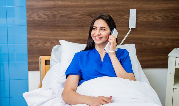 Patient talking on the phone in hospital bed. Young caucasian woman.