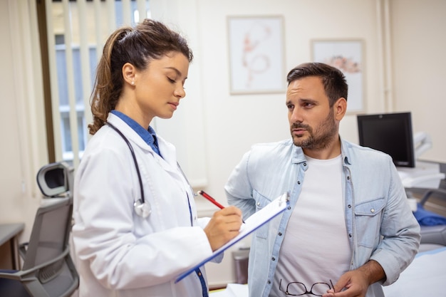 Patient telling physician about his pain and health problems during visit to hospital Young man complaining about back or kidney ache while sitting on examination bed at the doctor's office