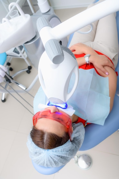 The patient undergoes a procedure for teeth whitening with an\
ultraviolet lamp