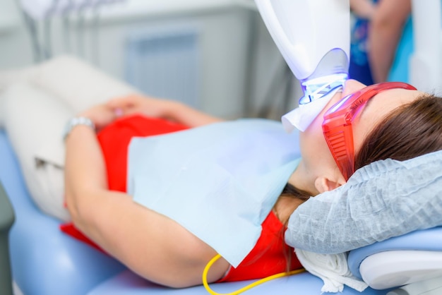 The patient undergoes a procedure for teeth whitening with an ultraviolet lamp