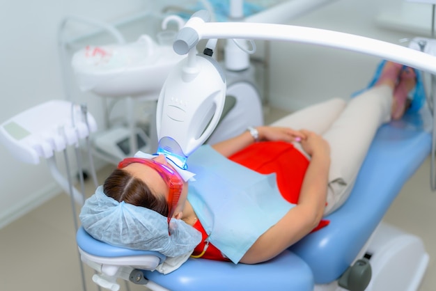 Пациент проходит процедуру отбеливания зубов ультрафиолетовой лампой.