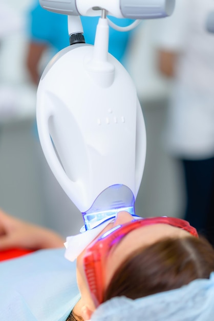 The patient undergoes a procedure for teeth whitening with an ultraviolet lamp