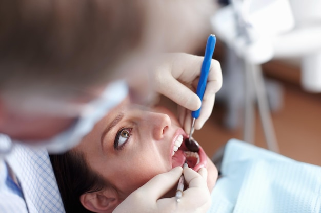 Пациент посещает стоматолога Высокий угол обзора стоматолога, проверяющего зубы пациентов