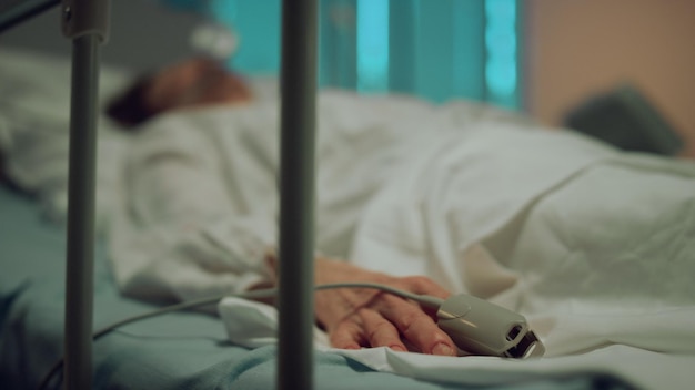 Patient with oxygen mask resting in hospital Pulse oximeter on finger closeup