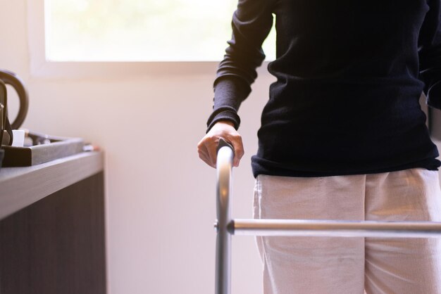 Patient woman hand holding walker trying to walk at home