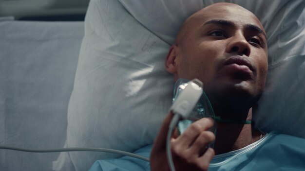 Foto patiënt zet een zuurstofmasker op, liggend op bed close-up pulsoximeter op de vinger