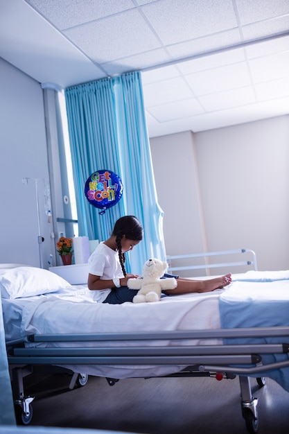 Patiënt zittend op bed met teddybeer