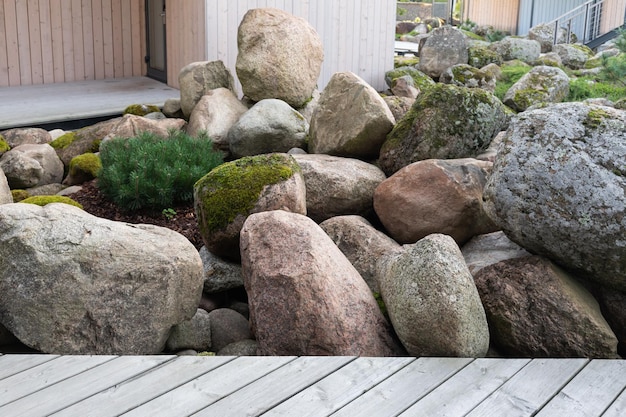 Patio met houten terras van een landhuis in Scandinavische stijl met bemoste rotsblokken