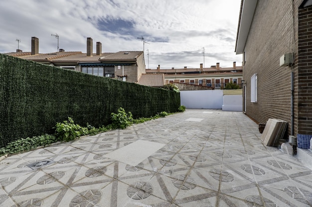 Photo patio of a singlefamily home with terrazzo floors surrounding the building built with dark brown cement bricks and a wall covered with green synthetic grass