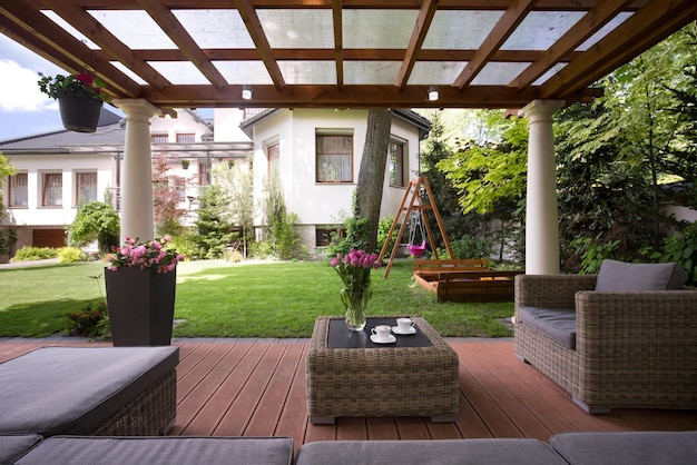 A patio with a pergola and a table with chairs and a swing set.