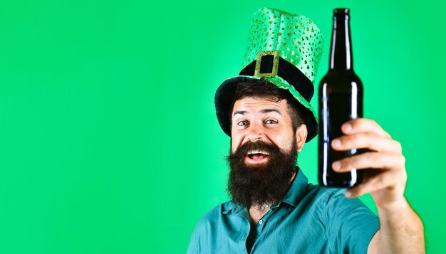 Photo patricks day celebration smiling bearded man in green hat with bottle of beer on saint patrick day