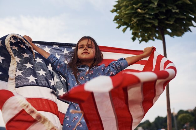 Foto bambina patriottica con bandiera americana in mano