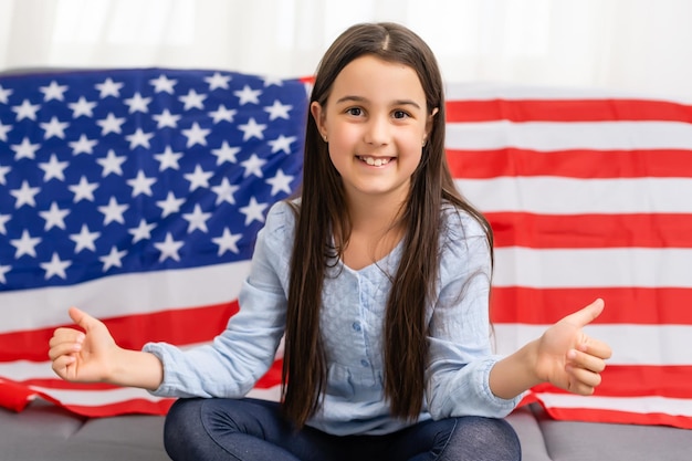 Patriotic holiday. Happy kid, cute little child girl with American flag. USA celebrate 4th of July.