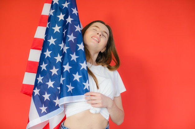 Patriotic holiday Happy young woman with American flag on red background USA celebrate 4th of July