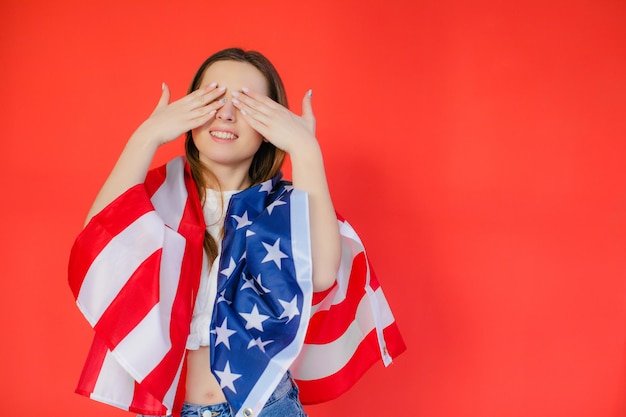 Патриотический праздник Счастливая молодая женщина с американским флагом на красном фоне США отмечают 4 июля