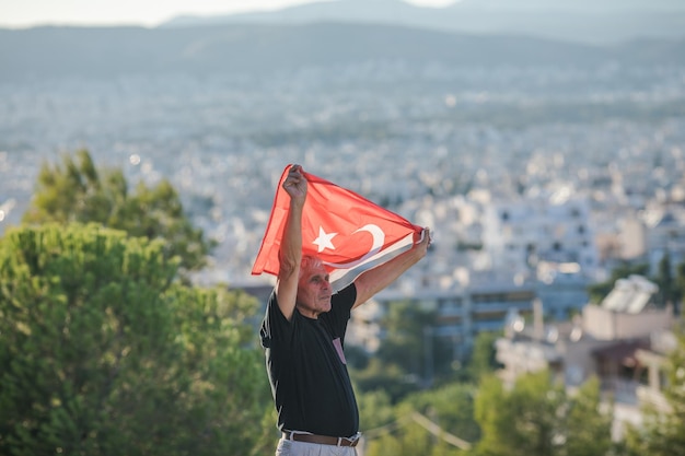 Patriotic senior man celebrates Turkish independence day with a national flag in his hands Constitution and Citizenship Day