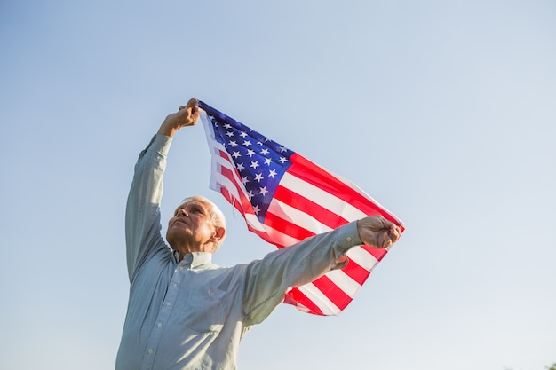 アメリカの国旗を保持している愛国心が強い年配の男性