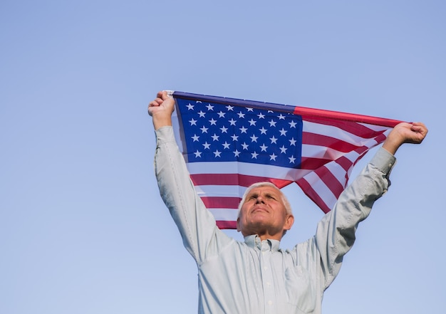 Patriotic senior man with a national flag in his hands.