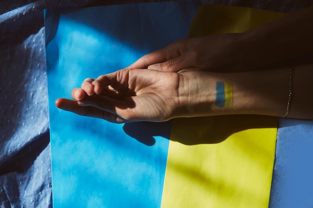 patriotic ukrainian flag on hands with shadows ukrainian flag background with copy space stop the war in ukraine stop russian aggression stand with ukraine sensation pray for ukraine