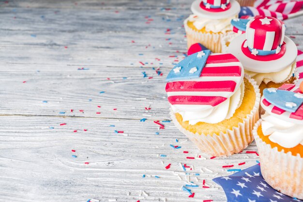 Photo patriotic usa cupcakes over flags on wood table