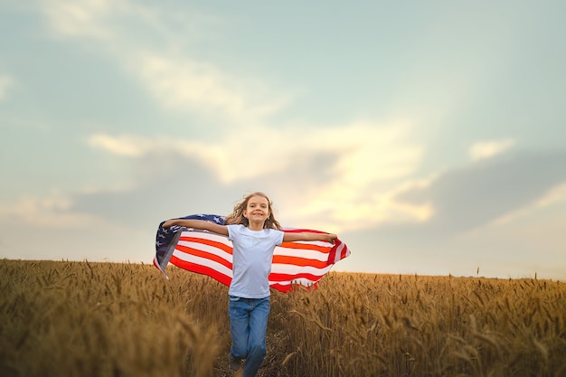 Foto patriottisch meisje dat een amerikaanse vlag draagt in een tarweveld