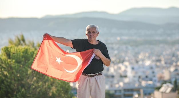 Patriottische senior man viert Turkse onafhankelijkheidsdag met een nationale vlag in zijn handen Grondwet en burgerschapsdag