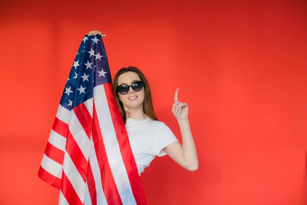 Patriottische vakantie Gelukkige jonge vrouw met Amerikaanse vlag op rode achtergrond VS viert 4 juli