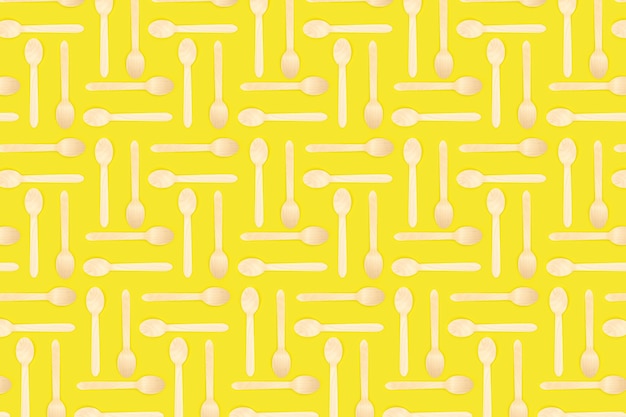 Patroon van bamboe wegwerp picknicklepels. Labyrint gemaakt van houten lepels op een gele achtergrond