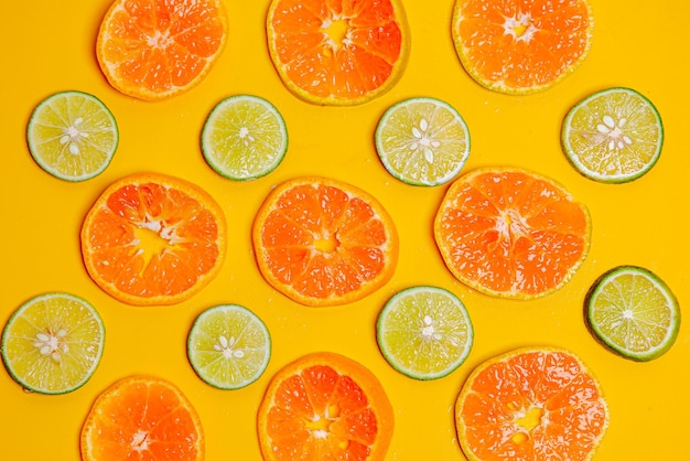 Patroon van oranje fruitschijfje en limoenschijfje op gele achtergrond Leuk behang voor zomerconcept